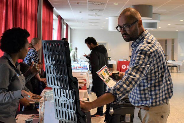 An attendee looks at Child and Youth Services flyers during the Benelux Employment and Career Expo Sept. 5, 2019, on SHAPE, Belgium. (DoD Photo)