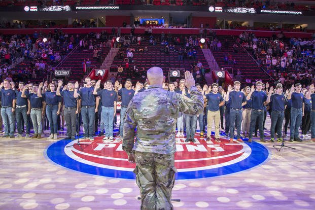 Army Colonel Jeffrey D. Witt, Chief of Staff of U.S. Army Tank-automotive & Armaments Command administers the Oath of Enlistment at a joint enlistment ceremony during halftime at the Detroit Pistons Hoops For Troops game.(U.S. Navy/Mass Communication Specialist 1st Class Stephen D. Doyle II)