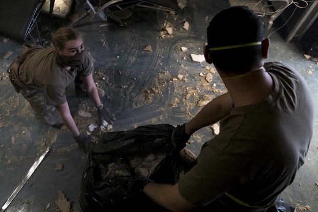 U.S. Air Force Senior Airman Olivia Gott, left, and 1st Lt. Felipe Cuesta, right, clear debris inside the passenger terminal the day after a Taliban-led attack at Bagram Airfield, Afghanistan, Dec. 12, 2019 (U.S. Air Force/Airman 1st Class Brandon Cribelar)