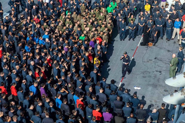 Sailors and Marines attend an all-hands on the deck of the USS America