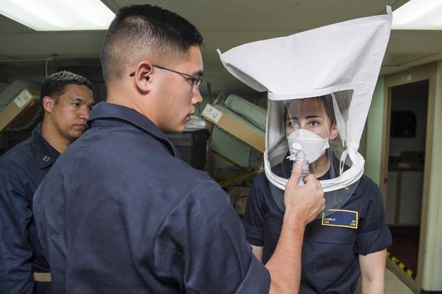 Hospital Corpsman 3rd Class Cleve Webb, performs a fit test with the N95 respirator mask on Lt. j. g. Danielle Ho, aboard hospital ship USNS Comfort.