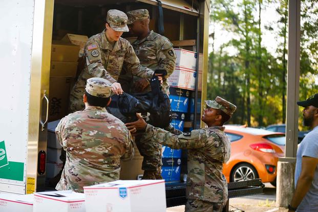 Soldiers with the 44th Medical Brigade prepare personal protective equipment and load transportation from Fort Bragg.