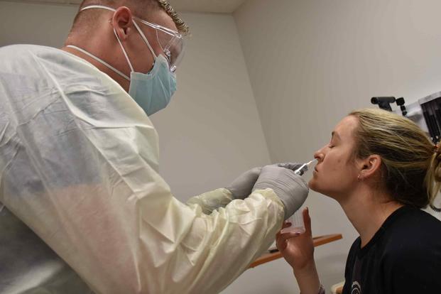 Pfc. Casey Tebo, a medic in the Womack Urgent Care, performs a COVID-19 test.