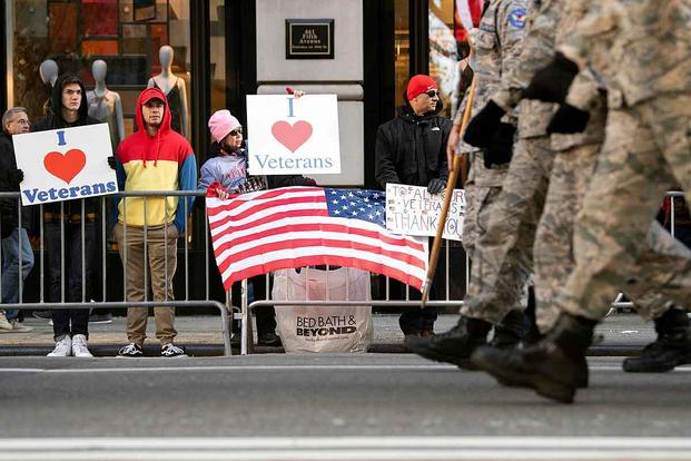 Spectators hold signs supporting veterans at the New York City Veterans Day Parade