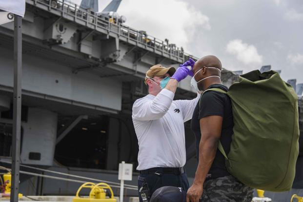 Sailors assigned to the USS Theodore Roosevelt are screened as they prepare to board.
