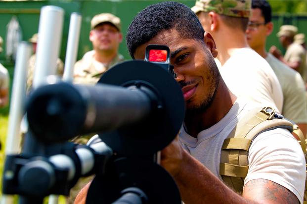 Senior Airman Johnny Hillary aims down on the scope of a drone defender rifle.