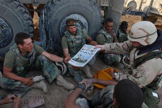 Command Sgt. Maj. John Sparks delivers copies of "Stars and Stripes" to Marines.