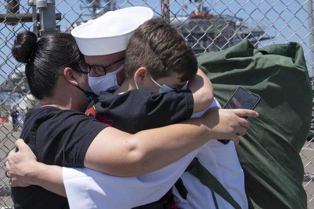 A sailor hugs his family following his return from deployment.