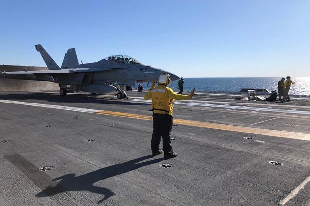 A crew member signals to an F/A-18 Super Hornet preparing for launch on the deck of the carrier Gerald R. Ford Nov. 17, 2020 (Hope Hodge Seck/Staff)