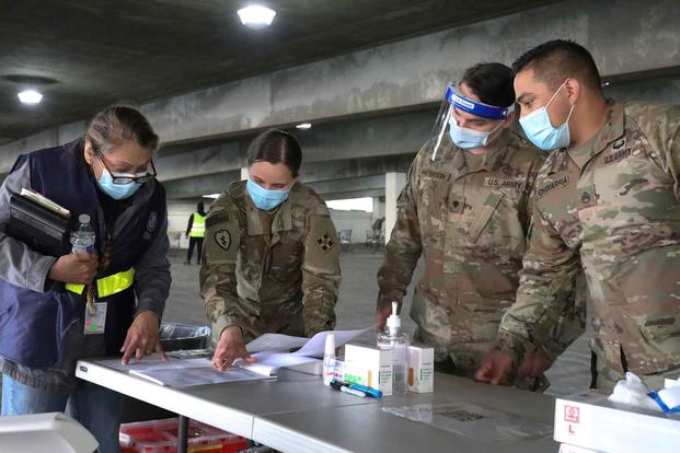 U.S. Army Soldiers and a FEMA employe at a mass vaccination site.