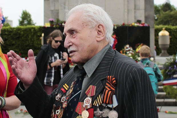 Soviet war veteran David Dushman, 92, center, speaks to people holding Ukrainian flags
