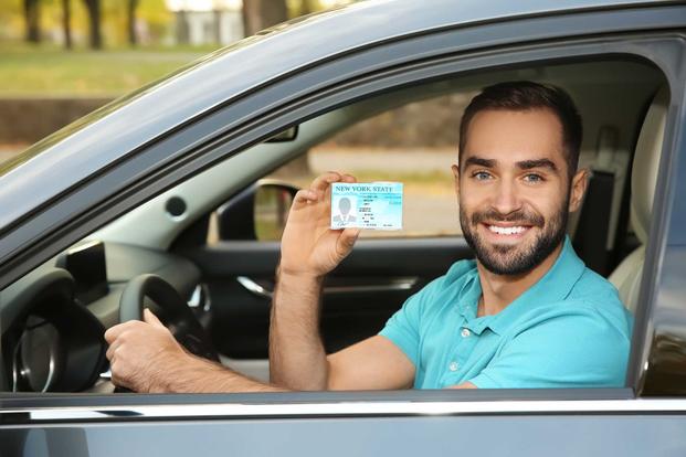 Man in car holding drivers license