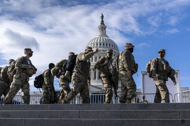 National Guard troops walk in front of the Capitol.