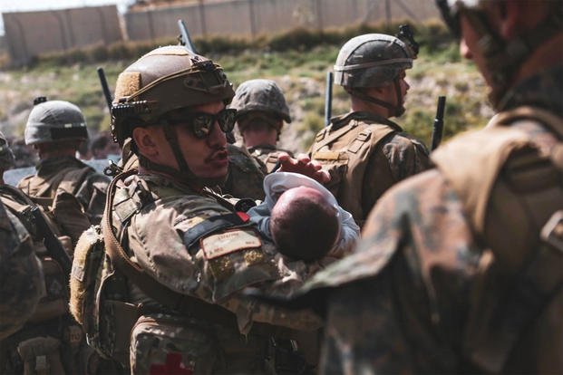 U.S. military service members comfort infants at Hamid Karzai International Airport in Kabul, Afghanistan.