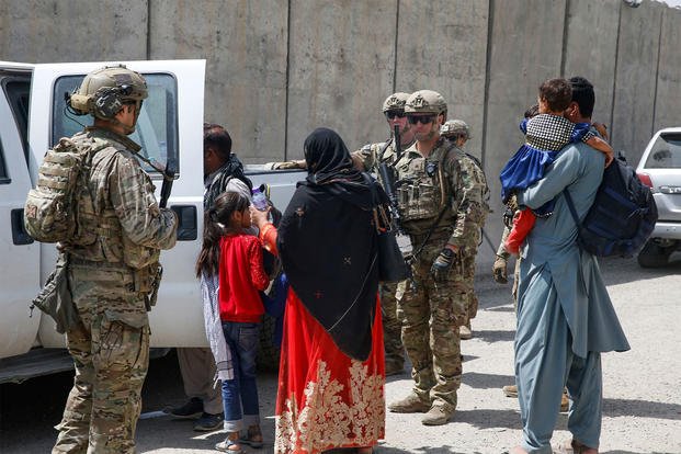 U.S. Army soldiers assigned to 3rd Brigade, 10th Mountain Division escort a young family to the terminal for check-in at Hamid Karzai International Airport in Kabul, Afghanistan.
