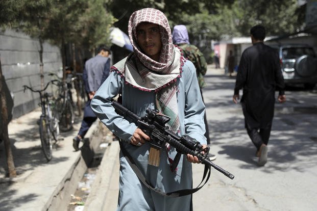 A Taliban fighter stands guard at a checkpoint in the Wazir Akbar Khan neighborhood,