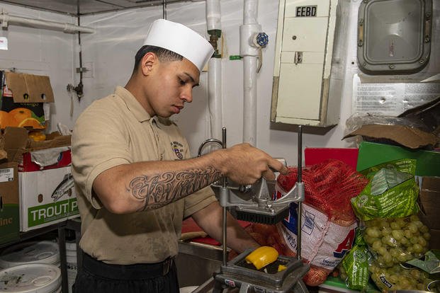 A sailor chops vegetables.