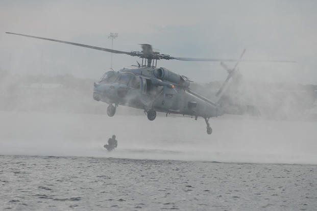 A Navy SEAL exits an SH-60 Seahawk helicopter and enters the water.