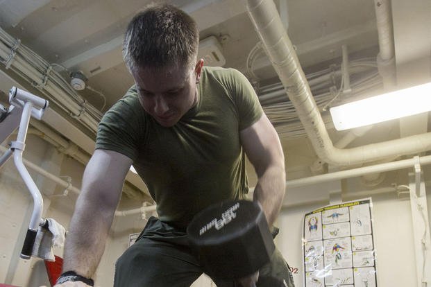 A noncommissioned officer performs a 100-pound dumbbell row.