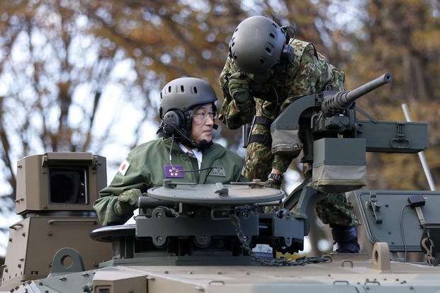 Japan's Prime Minister Fumio Kishida rides on a Japan Ground Self-Defense Force Type 10 tank.