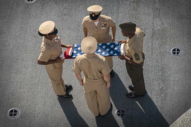 A Marine and sailors fold an American flag during a 9/11 remembrance ceremony aboard the USS Portland in the Indian Ocean.