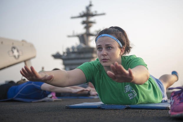 Sailors receive instruction during a yoga class.