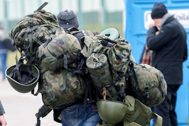 A man carries military combat gear as he leaves Poland to fight in Ukraine.