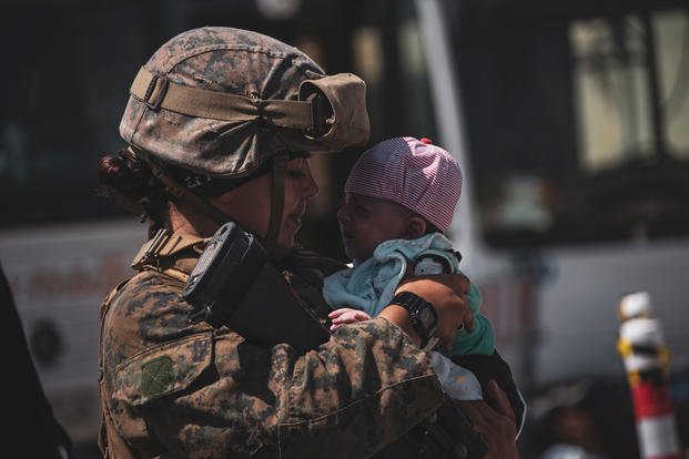 Marine calms down an infant at Hamid Karzai International Airport, Afghanistan