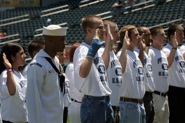 Delayed Entry Program recruits stand at attention as they take the oath of enlistment on the field during a Sacramento River Cats minor-league baseball game against the Tucson Padres during Sacramento Navy Week.