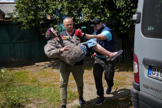 A woman is carried from her home in an evacuation by volunteers in Ukraine. 