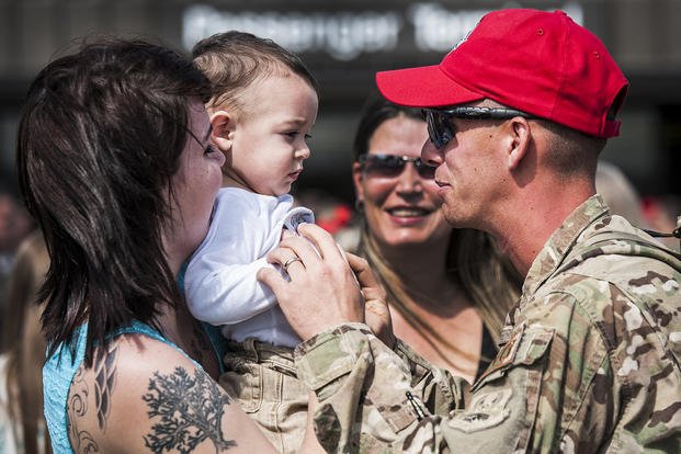 A senior airman embraces his wife and son after returning from deployment.