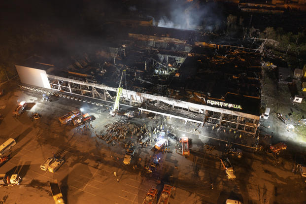 firefighters work to extinguish a fire at a shopping center burned after a rocket attack in Kremenchuk, Ukraine