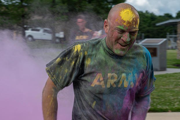 A soldier with the New Jersey Army National Guard runs through the finish line during the Pride 5K Color Walk/Run on Joint Base McGuire-Dix-Lakehurst, N.J., June 9, 2022. (Airman Simonne Barker / U.S. Air Force) A soldier crosses the finish line in Pride 5K