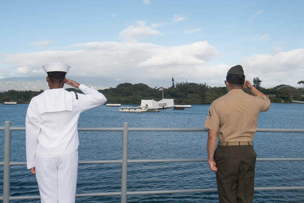 A sailor and a Marine render honors while passing the USS Arizona memorial at Pearl Harbor.
