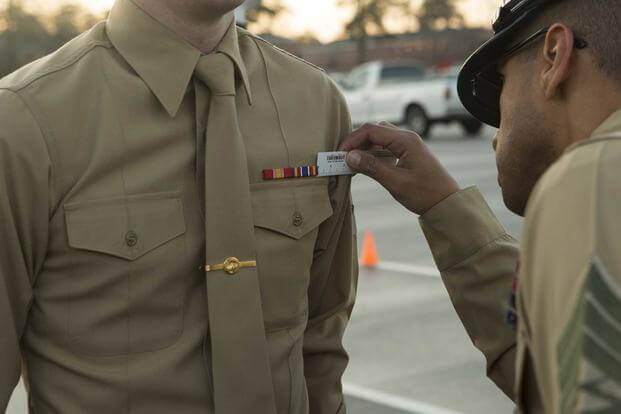 A ground communications technician measures a corporal’s ribbons.