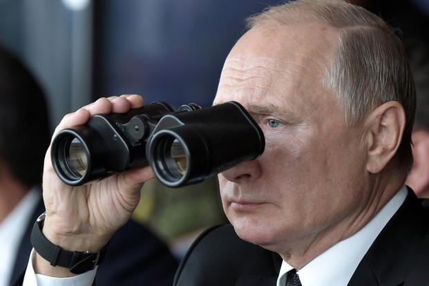 Russian President Vladimir Putin holds binoculars while watching the military exercise