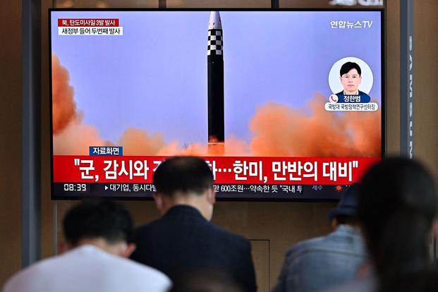 A television shows a news broadcast with file footage of a North Korean missile test.
