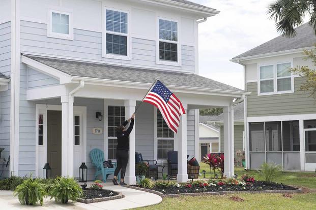 A resident at a Balfour Beatty Housing unit raises the American flag.