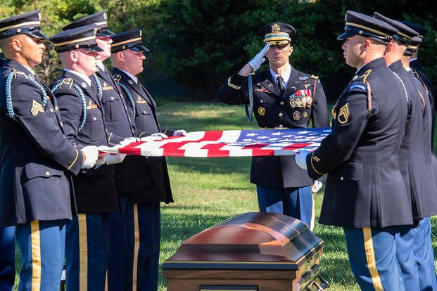 Soldiers prepare to fold the national flag during a full honors funeral at Arlington National Cemetery.