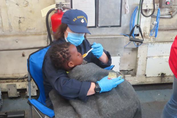 A Coast Guard member feeds a child.