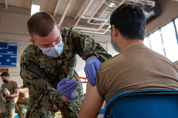 Hospital Corpsman 3rd Class Joseph Casassa administers a COVID-19 vaccine to Logistics Specialist Seaman Rix Zhang onboard Naval Station Norfolk.
