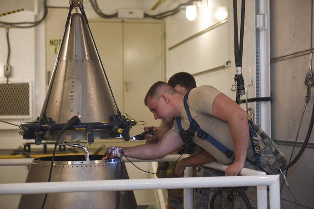 Airmen inspect the cable connections of an intercontinental ballistic missile.