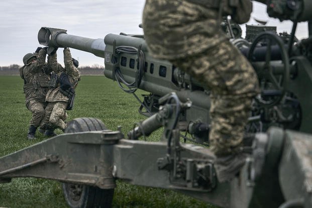 Ukrainian soldiers prepare a U.S.-supplied M777 howitzer to fire at Russian positions.