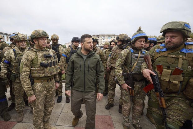 Ukrainian President Volodymyr Zelenskyy, center, is surrounded by soldiers during his visit in Izium, Kharkiv region