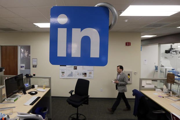 A LinkedIn employee walks past a company logo at the company's headquarters in Mountain View, Calif.