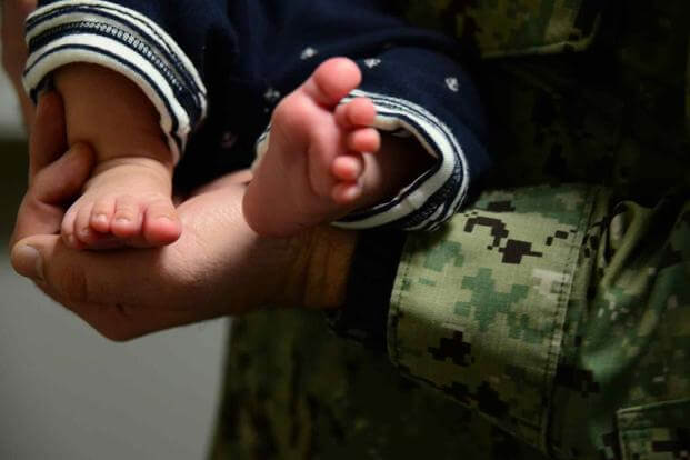 A U.S. Coast Guard Reserve member cradles his newborn son.