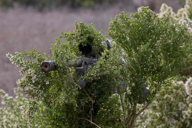 A Marine attending the Prescout Sniper Course camouflages his rifle.