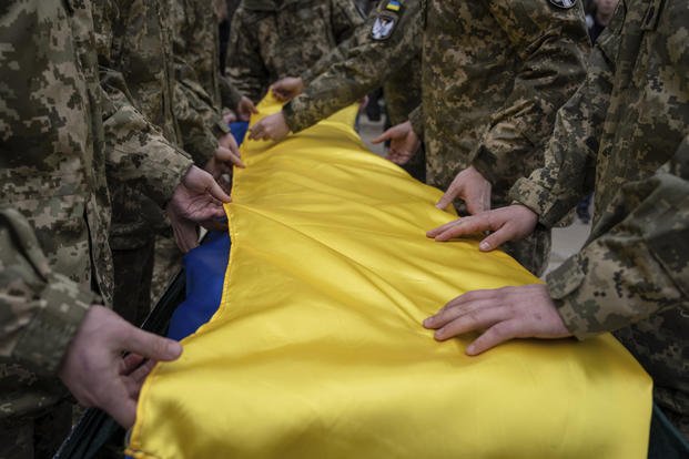 Ukrainian servicemen fold the national flag over coffin