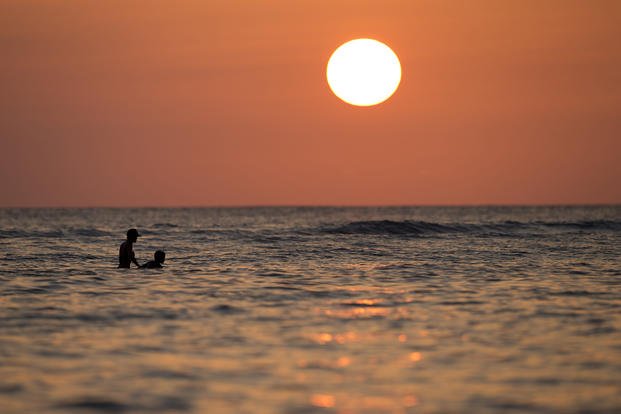 Swimmers float in the Pacific Ocean as the sun sets off Waikiki Beach in Honolulu. 