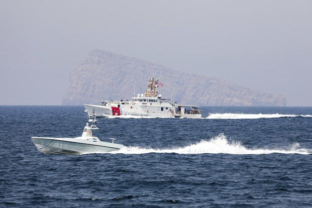 A U.S. Navy L3 Harris Arabian Fox MAST-13 drone boat and the U.S. Coast Guard cutter USCGC John Scheuerman